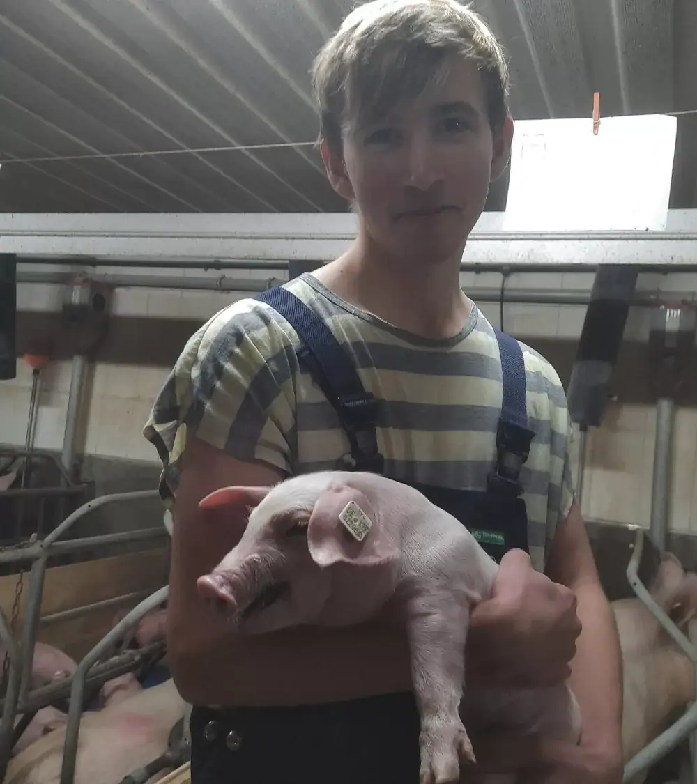 Junger Mann hält ein Schwein.