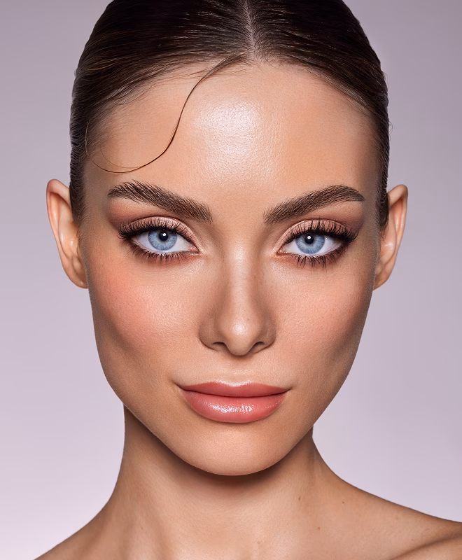 Person mit hellen blauen Augen und leichtem Make-up blickt in die Kamera