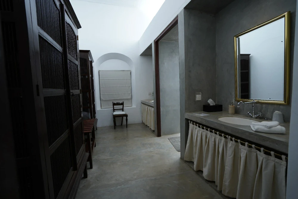 A view of the bathroom in Adigar's manor's Peacock Royal room, highlighting a sink and a stylish mirror.