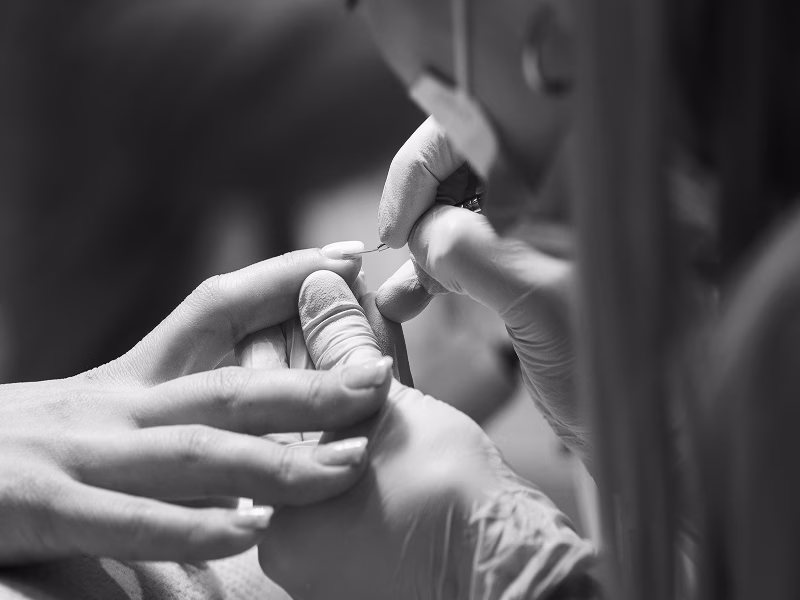 Maniküre: Nagelpflege mit feinen Werkzeugen, Hände und Handschuhe in einem Salonsetting.