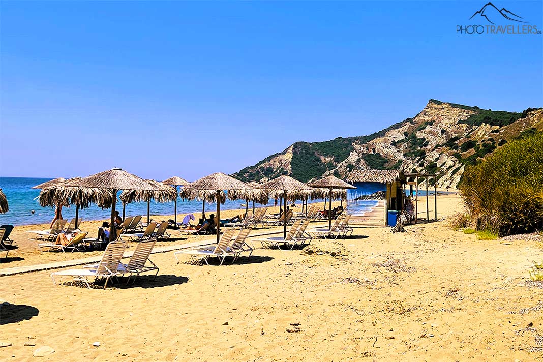 Liegen und Strohschirme zieren den goldfarbenen Sandstrand Arkoulidas Beach