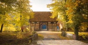 Hochzeitslocation Haus Runde 1 Backsteinscheune mit rotem Ziegeldach und blauen Türen – ein idealer Hochzeitsort für eine Freie Trauung in Münster Umgebung.