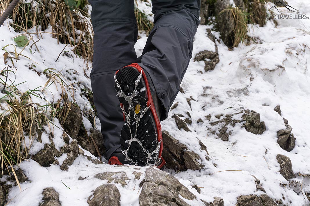 Die Snowline Spikes Pro auf Wanderschuhen auf einem eisigen Bergweg