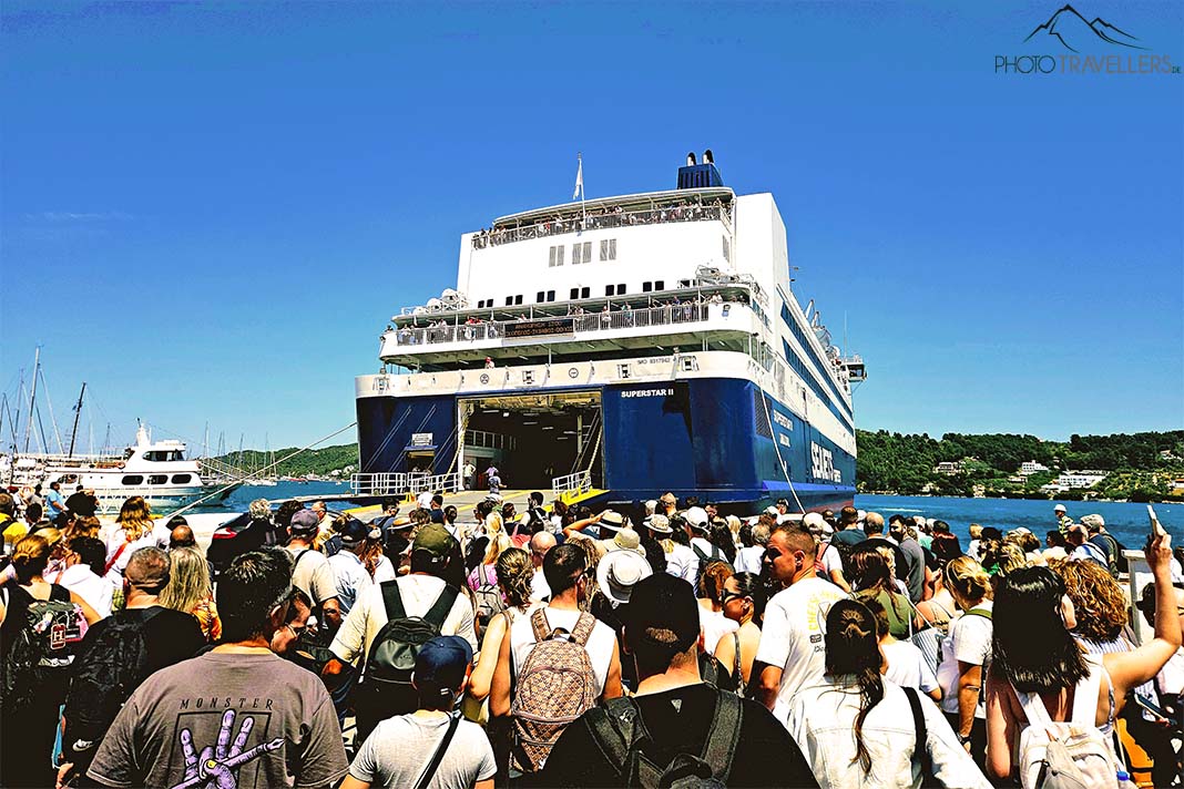 Viele Menschen entern am Hafen von Skiathos eine große Fähre mit blauem Bug