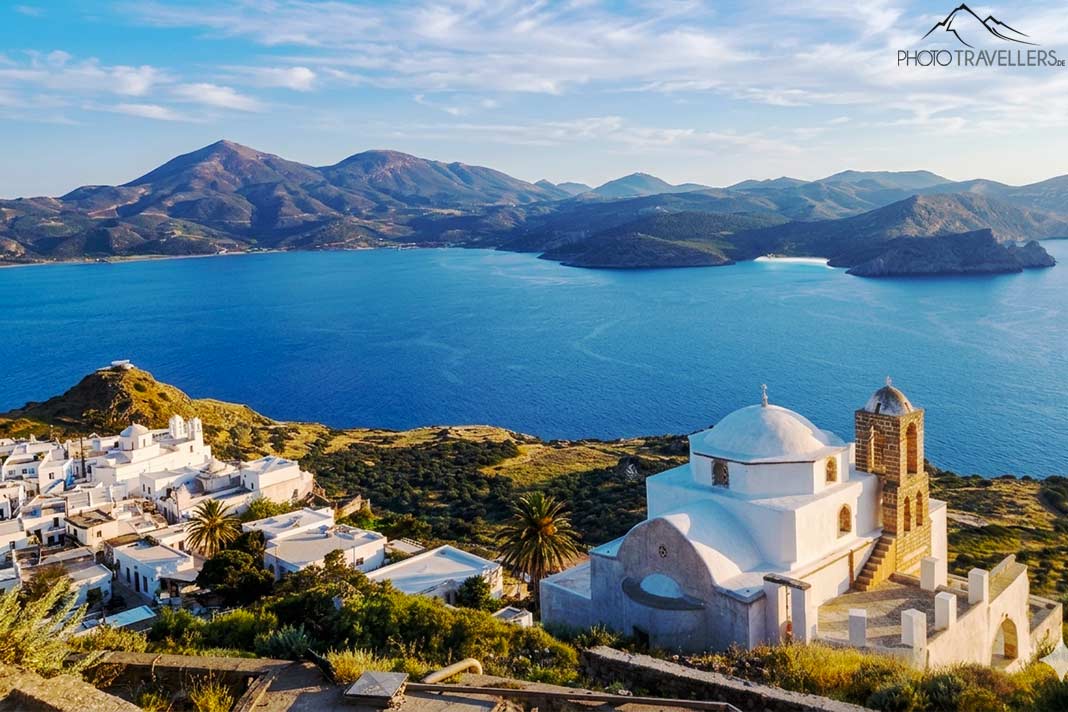 Blick von oben auf eine Kapelle in Plaka mit dem Meer und Bergen im Hintergrund
