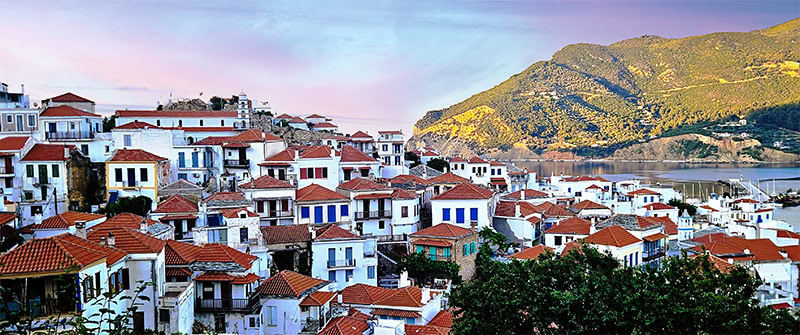 Blick auf die Häuser und Hügel von Skopelos-Stadt in der Abenddämmerung
