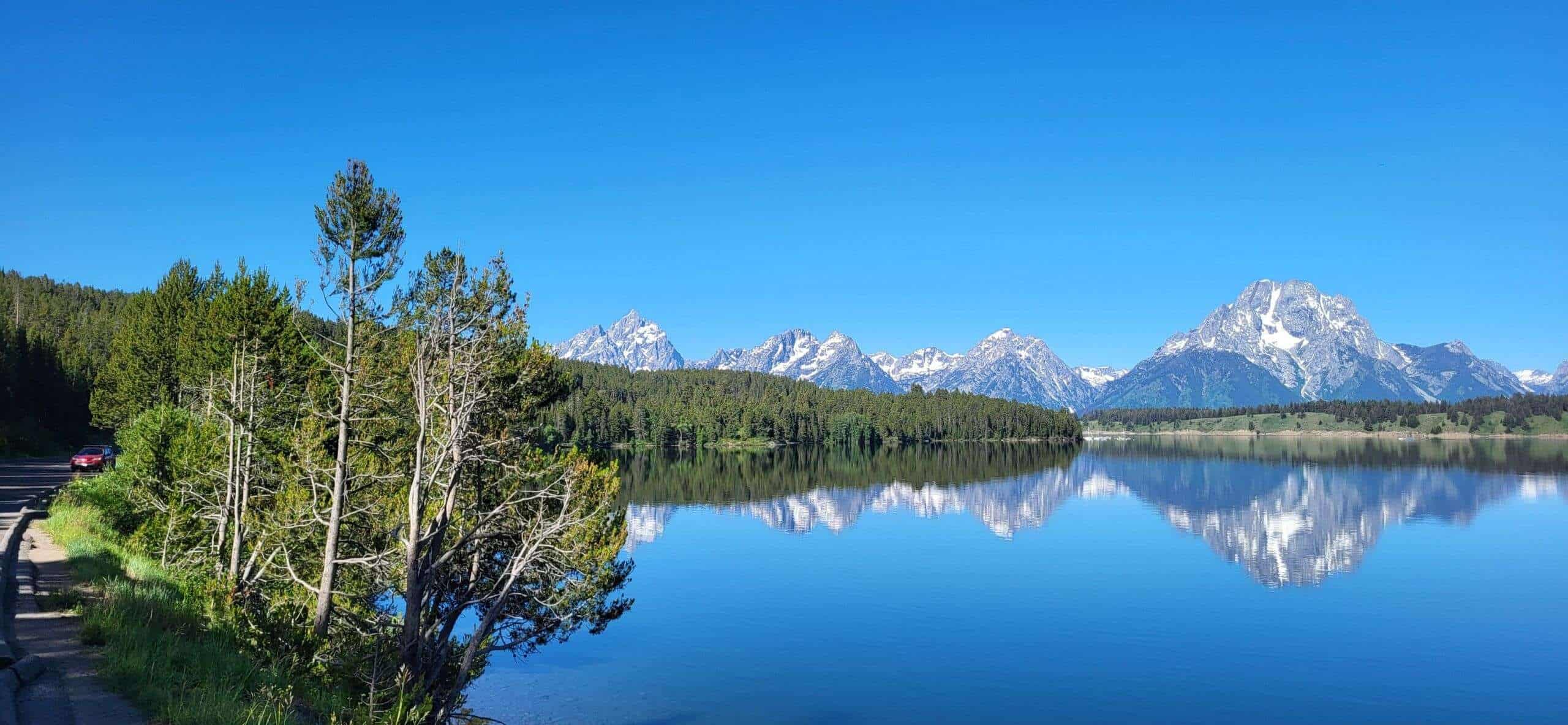 Majestätische Bergkulisse mit Schnee bedeckten Gipfeln und ruhigem See in Wyoming, USA, perfekt für Natur- und Landschaftsfotografie.