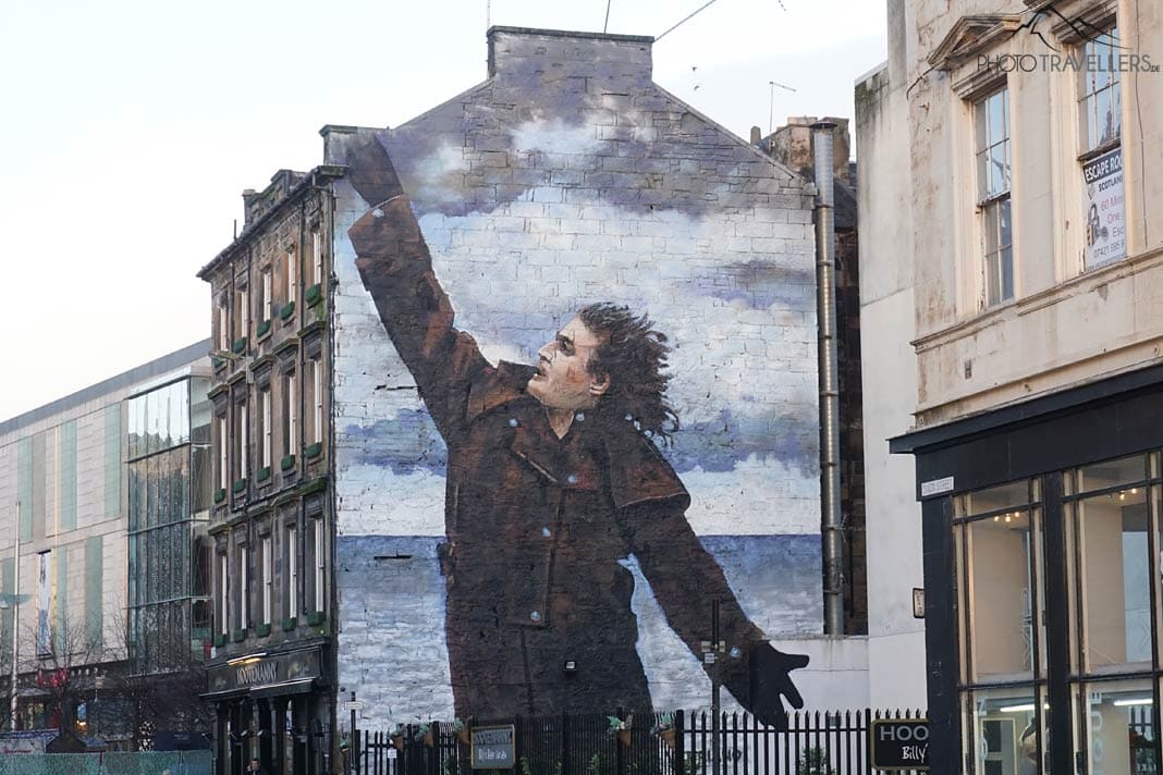 Ein großes Graffiti eines Mannes an einer Hauswand in Glasgow