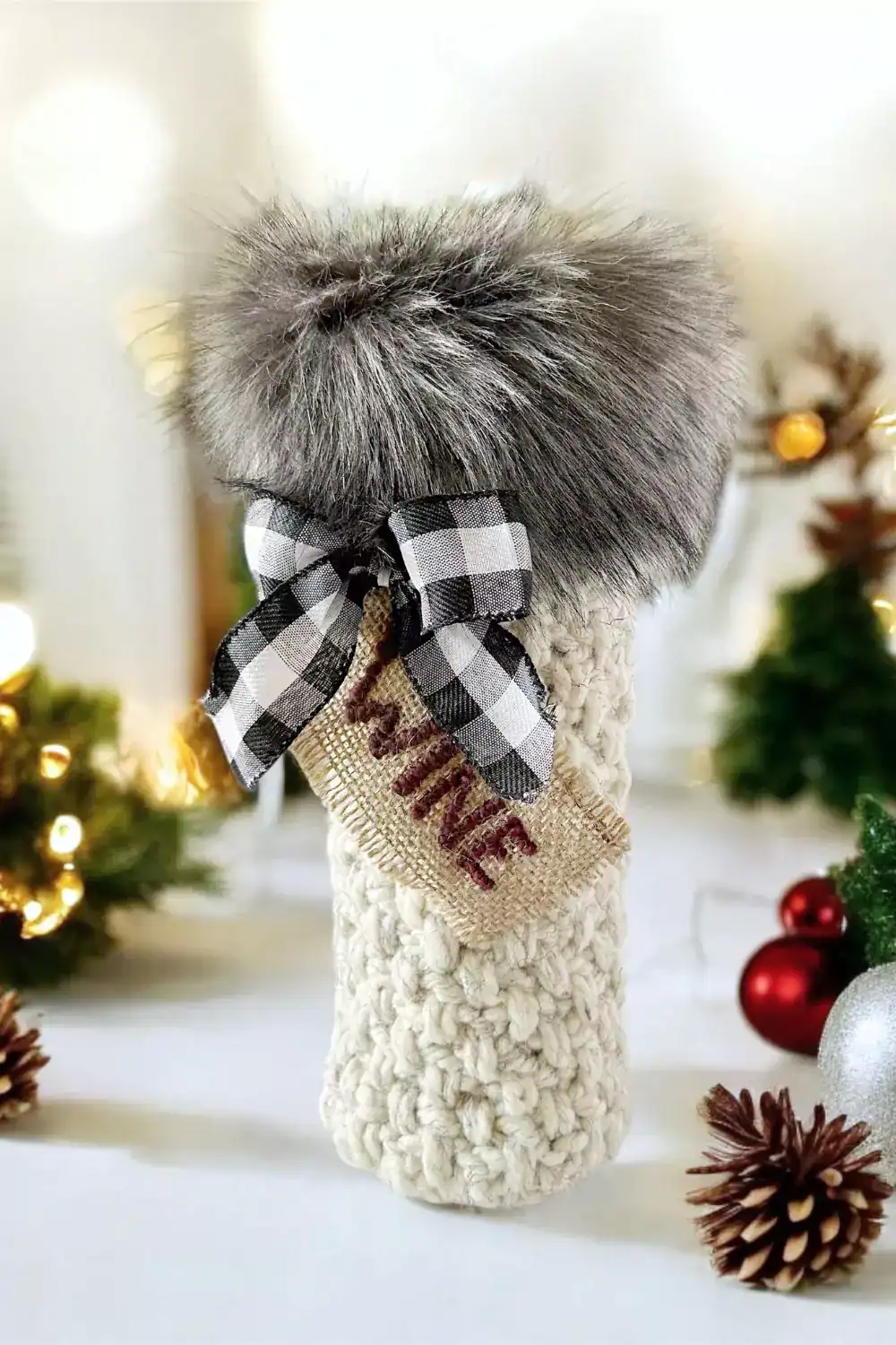 a bottle of wine and a crocheted wine bottle gift bag with faux fur fabric trim, checkered bow and wine tag - christmas background