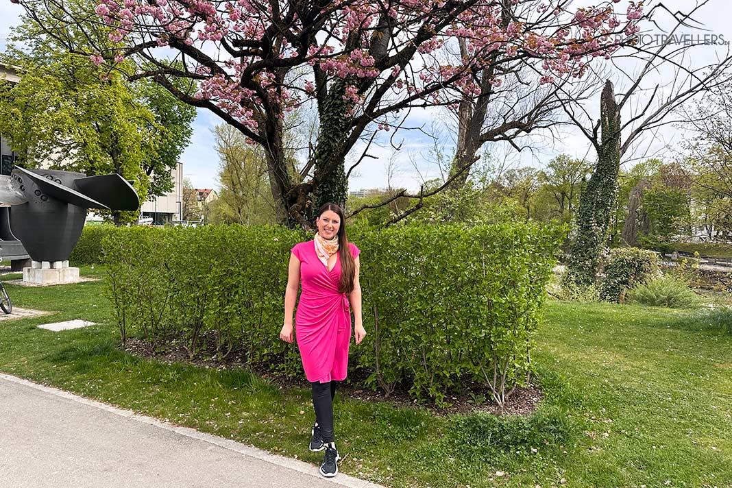Reisebloggerin Biggi Bauer in einem rosa Kleid vor einem blühenden Kirschbaum vor dem Deutschen Museum in München