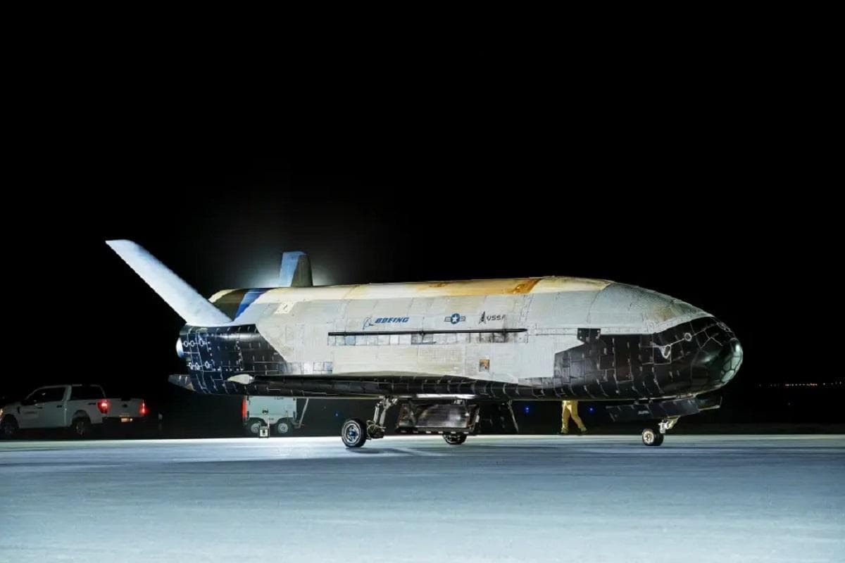 The X-37B Space Force orbital vehicle, a reusable unmanned spacecraft, rests on the Vandenberg landing strip at night. The Boeing-built craft, with its distinctive shape, shows signs of a long space mission. The word "BOEING" is visible on the side.