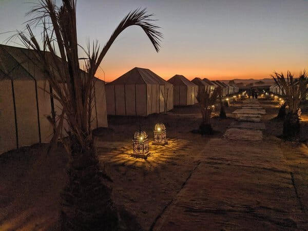 Tienda de campaña en el desierto con iluminación suave y palmeras, ideal para experiencias únicas en.