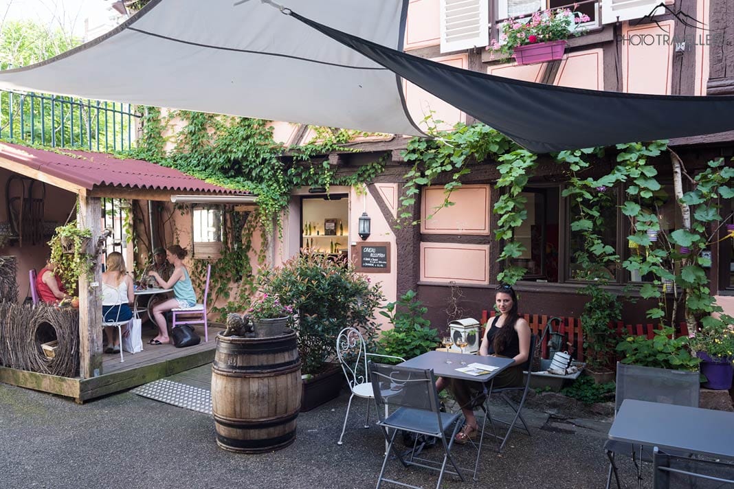 Reisebloggerin Biggi Bauer sitzt an einem Tisch im Innenhof des Maison Martin Jund in Colmar