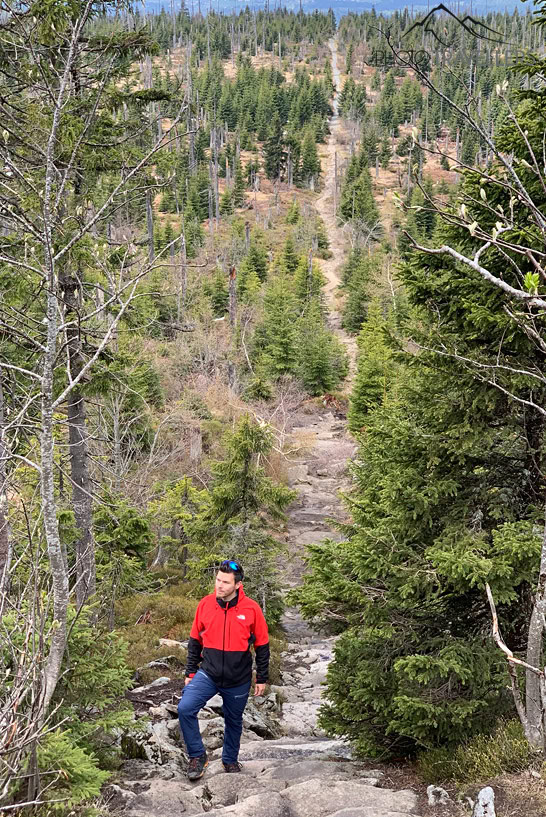 Reiseblogger Florian Westermann auf einer Stufe der bekannten Himmelsleiter im Bayerischen Wald mit dem Blick über die Landschaft