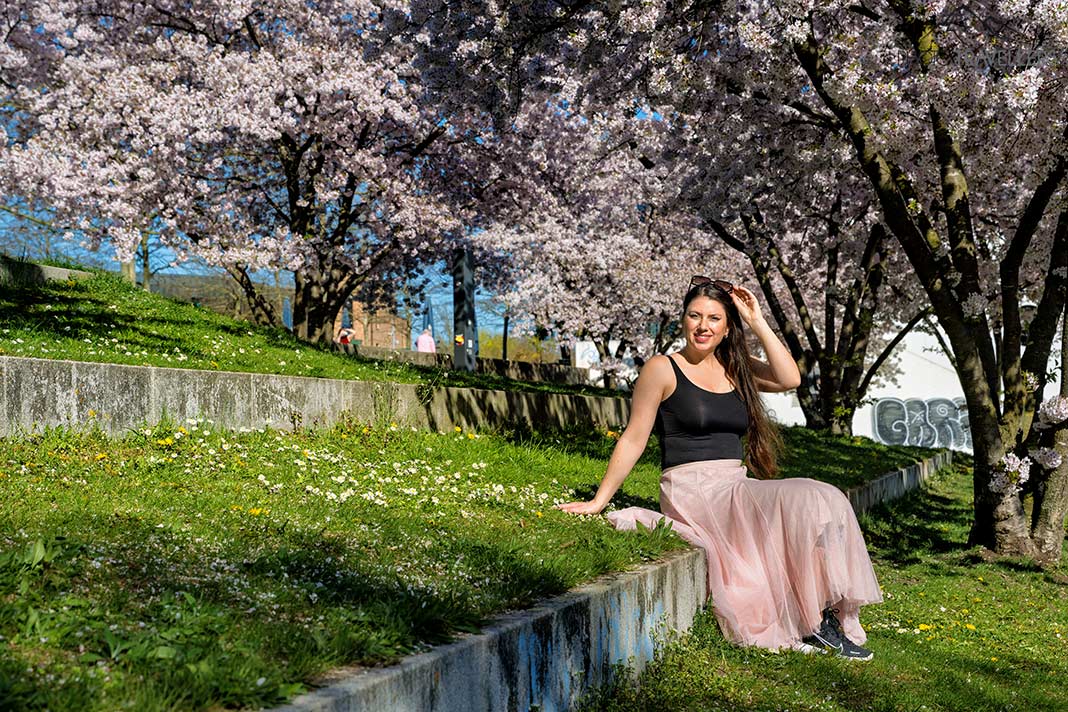 Reisebloggerin Biggi Bauer sitzt unter Kirschblüten im Petuelpark, München