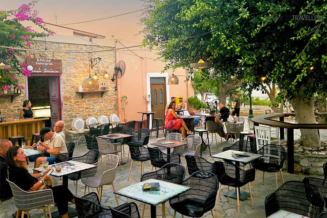 Eine Frau im roten Kleid sitzt unter einer Platane am Dorfplatz von Livadia