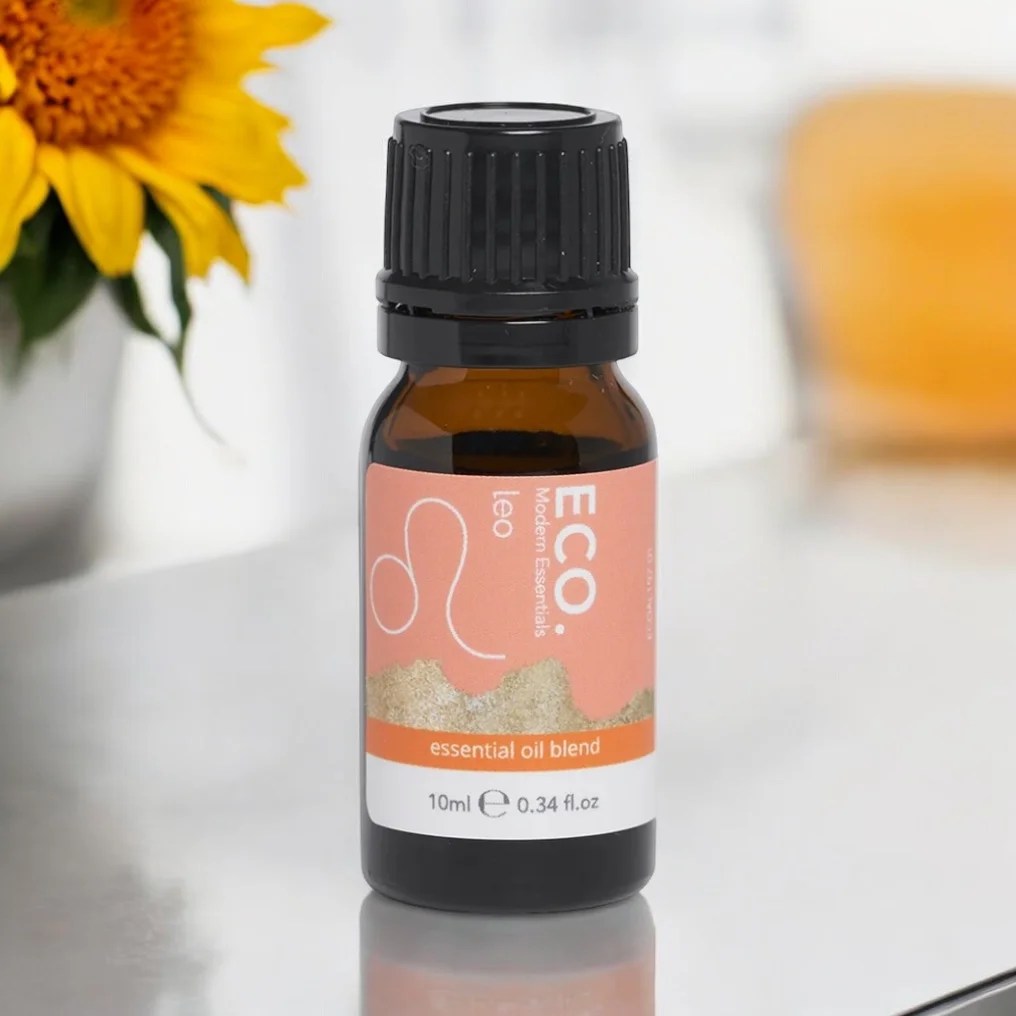 Leo Season 2 A small amber bottle of Leo Essential Oil Blend, 10ml, rests on a reflective surface with a softly blurred sunflower in the background, emphasizing the blend’s vibrant energy.
