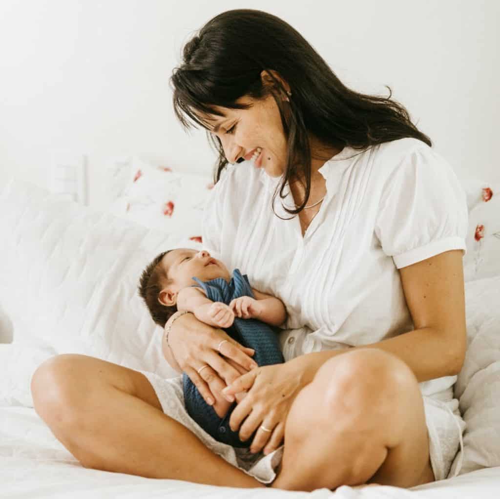 pexels-jonathan-borba-3763585 A mother smiling down at her baby laying cradled in her lap