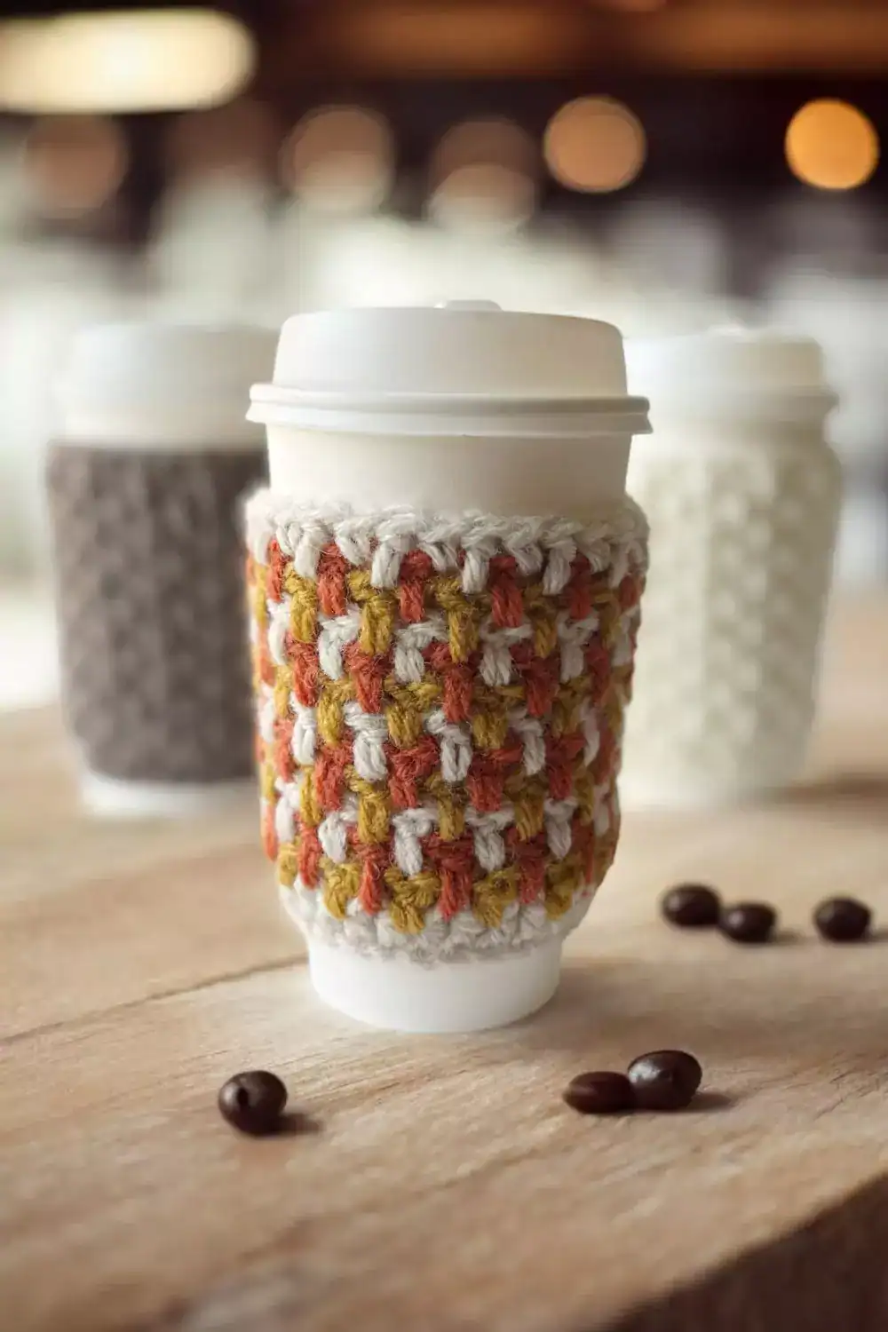a group of crochet coffee cozies in fall colours