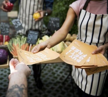 People Handing Out Promotion Brochure to Customer