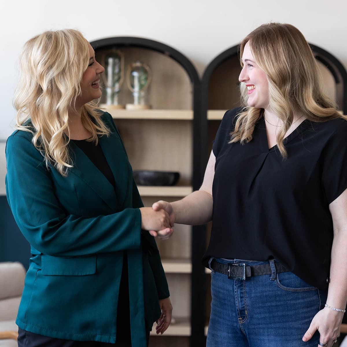 Two women shaking hands in a professional setting, representing marketing services.
