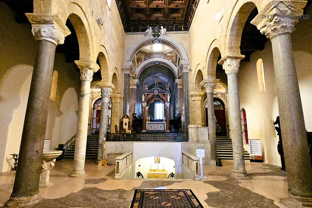 Hohe Säulen mit Mauerbögen aus hellem Stein umgeben den Altar der Kathedrale von Taranto