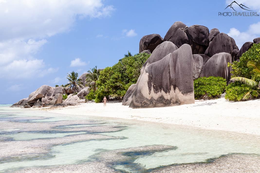 Eine Urlauberin im Bikini am Strand Anse Source D'Argent auf La Digue, daneben riesige Granitfelsen