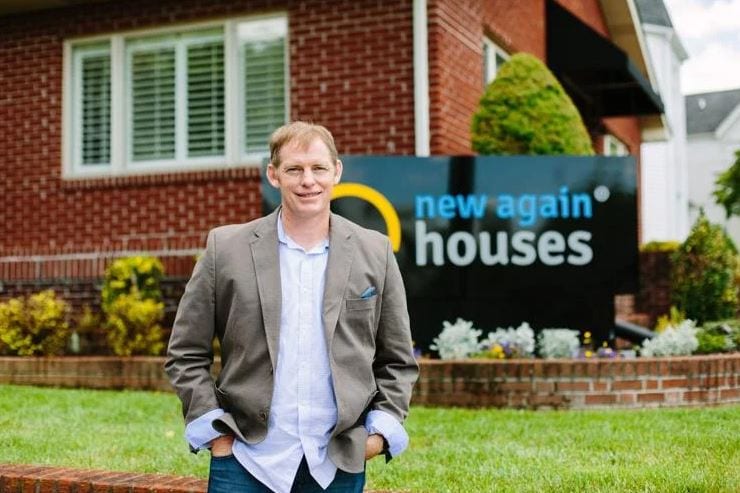 Matt Lavinder standing outside a brick home in front of a New Again Houses sign