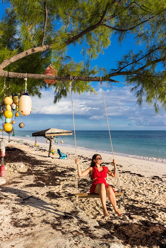 Reisebloggerin Biggi Bauer in einem roten Kleid auf einer Schaukel am Strand auf den Bahamas