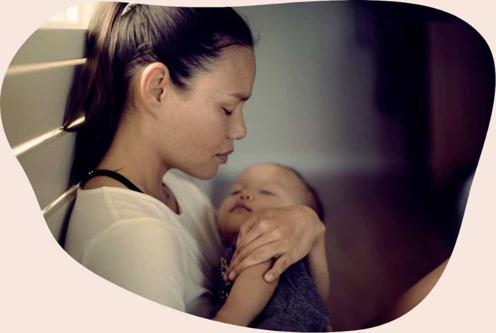 Mother holding sleeping baby in a dark room