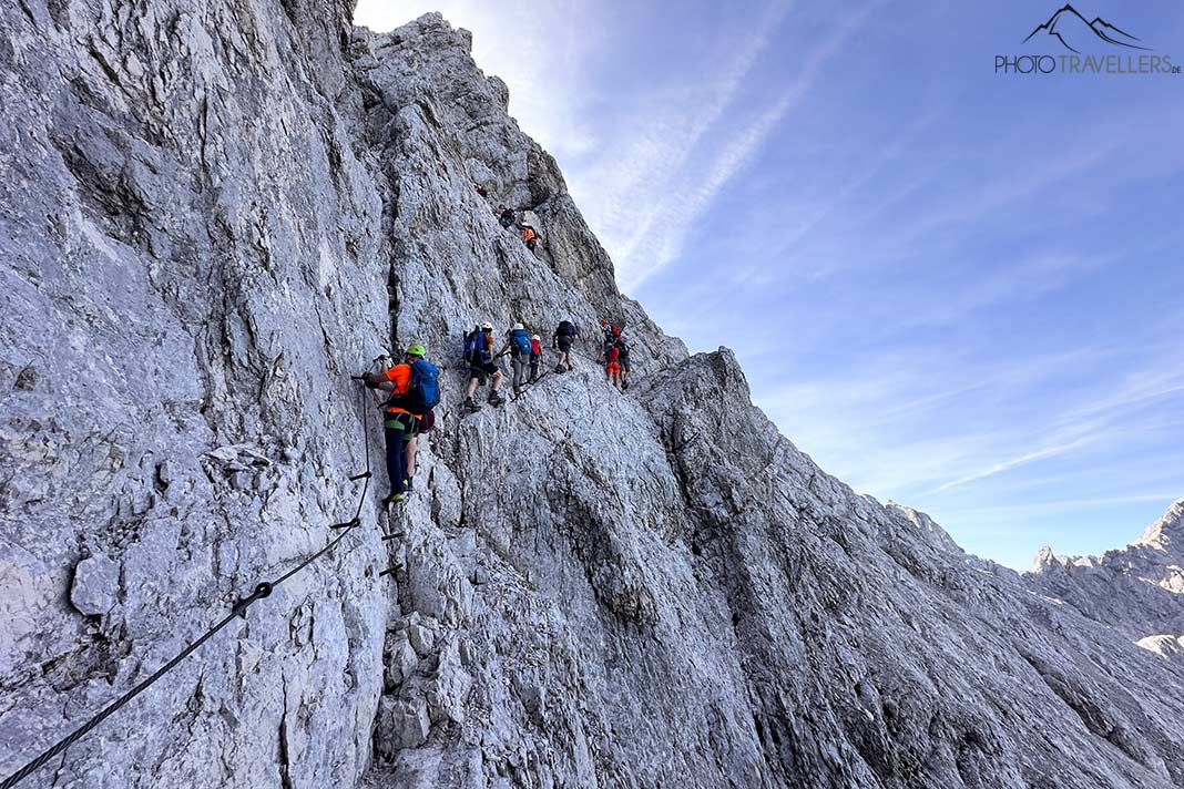 Mehrere Klettersteiggeher in der steilen Felswand unterhalb des Alpspitz-Gipfels