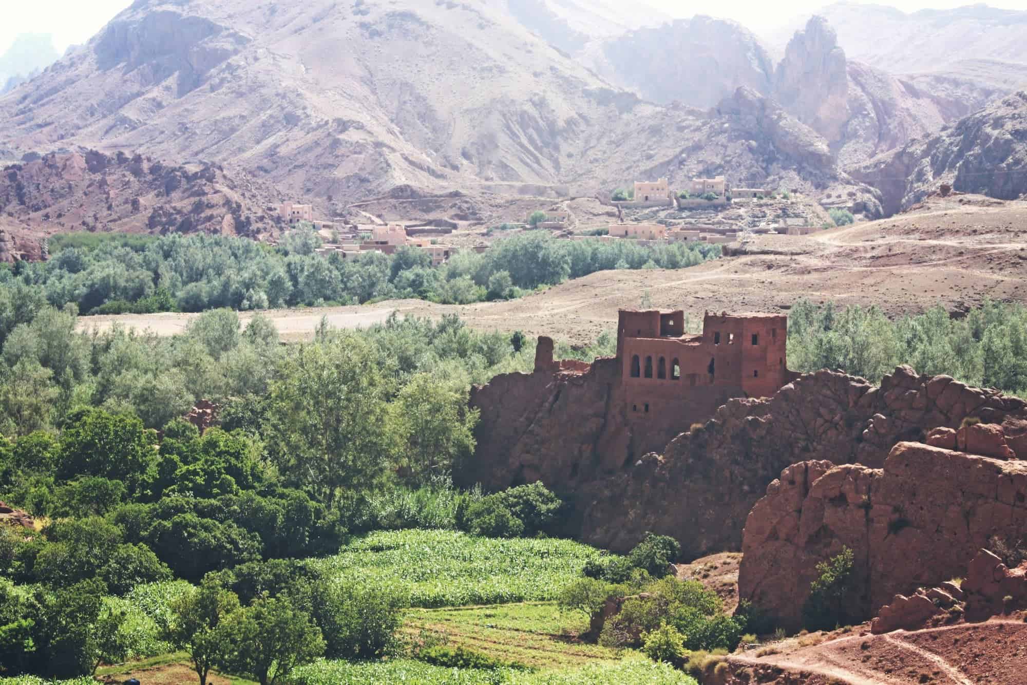 Paisaje de montañas y oasis en Marruecos, con vegetación y construcciones tradicionales en un entorn.
