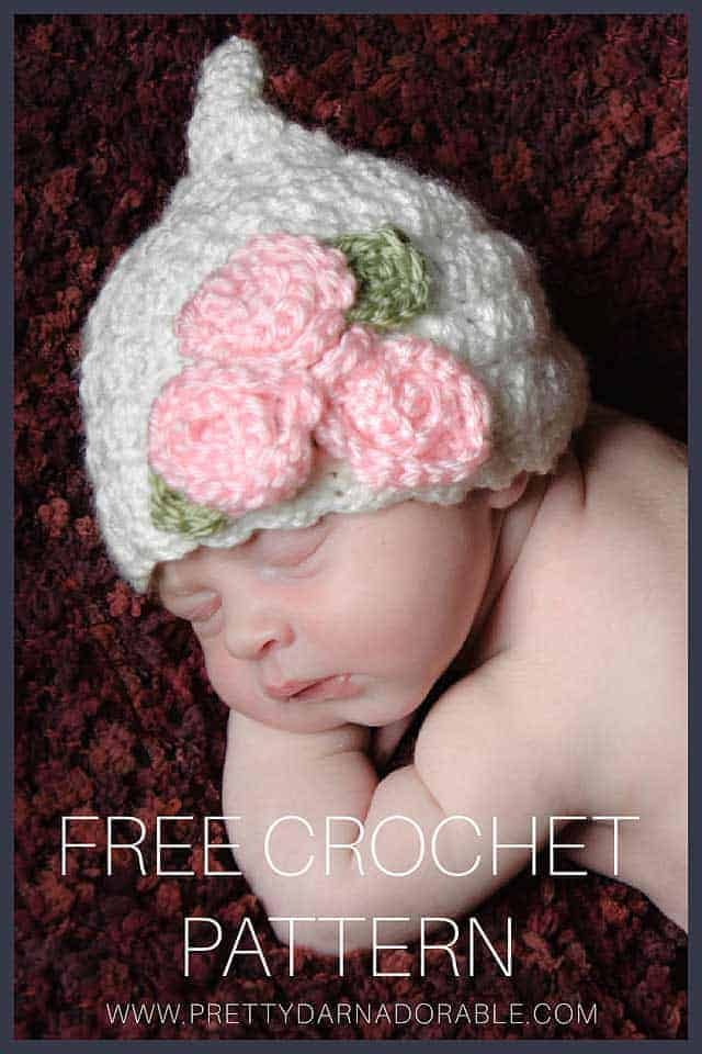 baby wearing white crochet pixie hat with pink roses