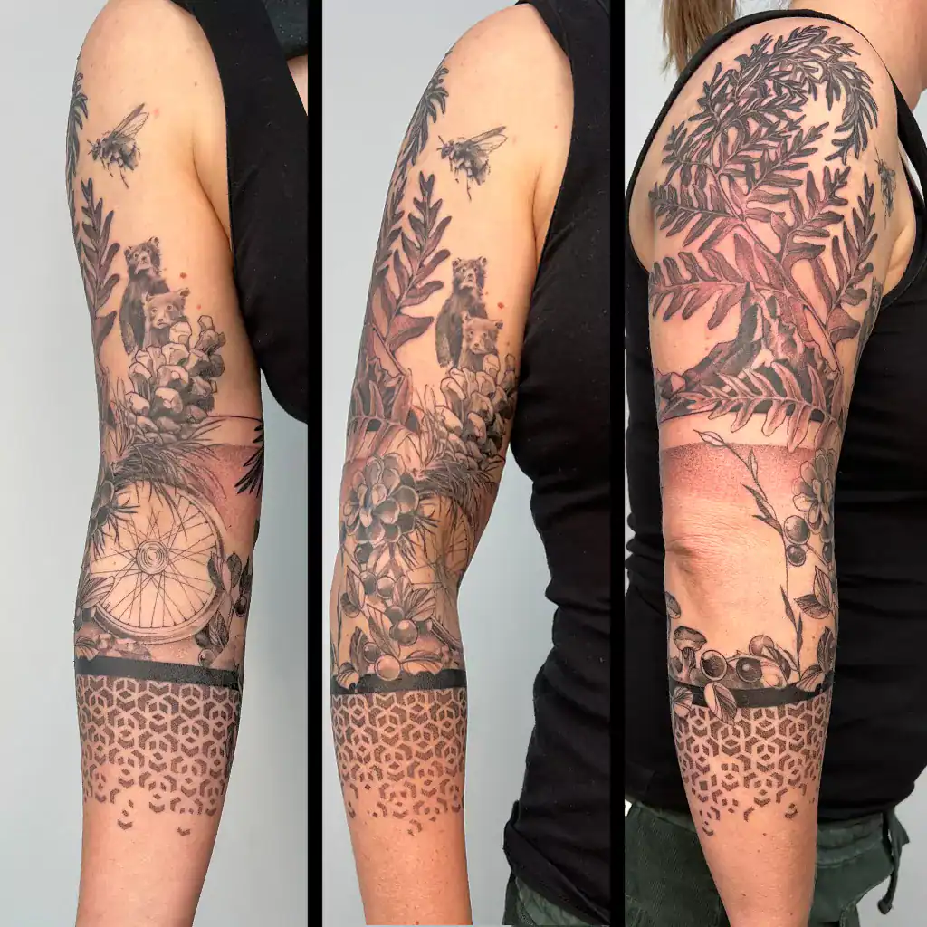 fineline tattoo dreiviertel sleeve mit Biene, Radspeiche, Bären und floralen Elementen