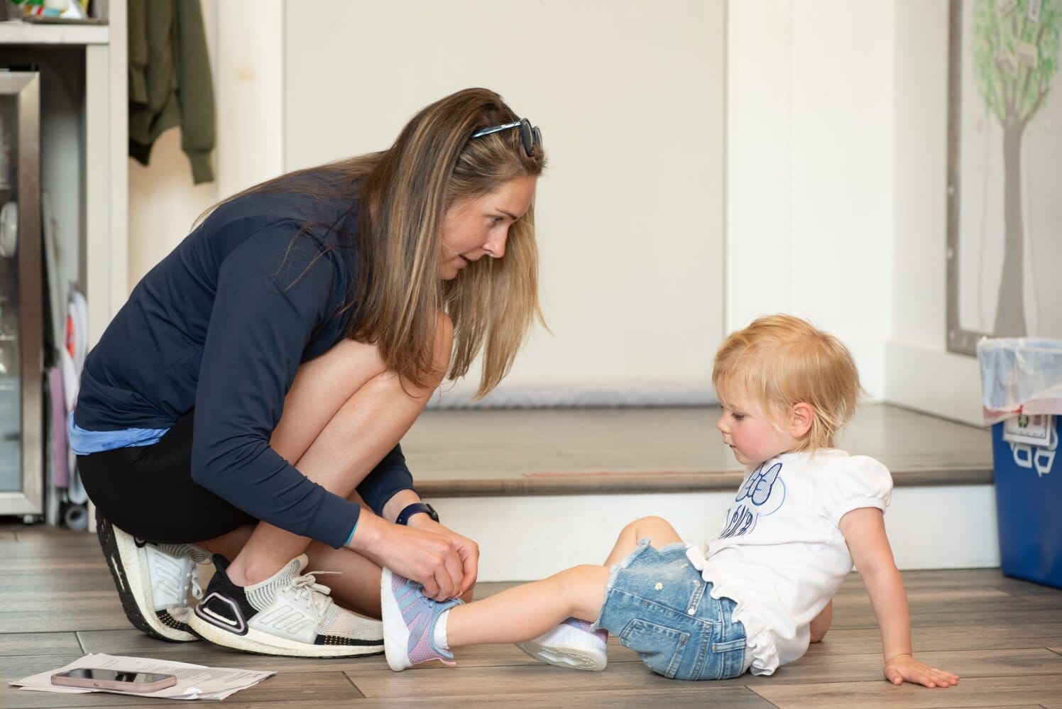 A woman tying a toddler's shoe