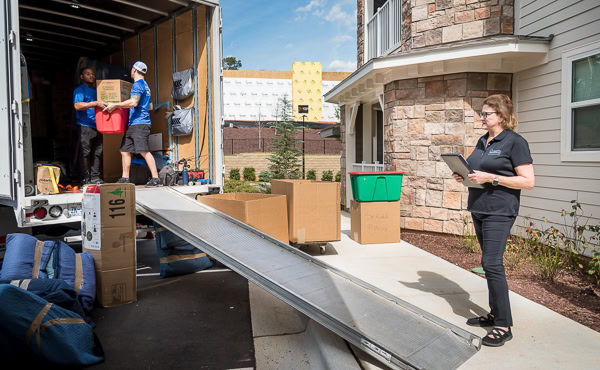 Smooth Transitions move team loads labeled boxes into a truck while a team member coordinates the move on a tablet