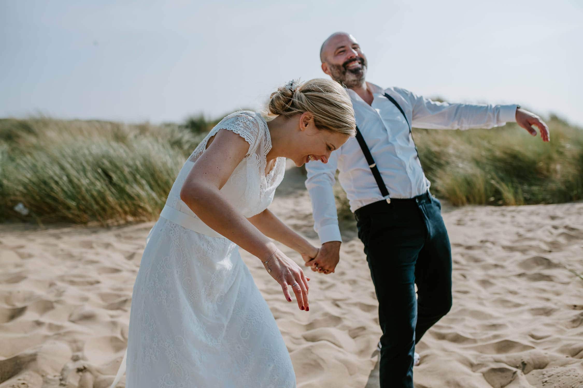 Fröhliches Brautpaar am Strand – authentische Hochzeitsreportage von Hochzeitsfotografin Köln Lachendes Brautpaar bei Strandhochzeit in Noordwijk