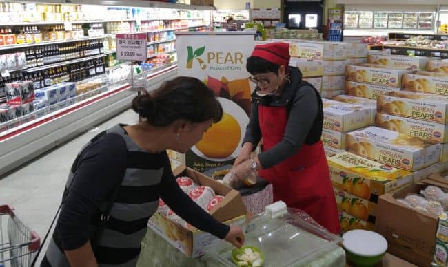 A customer at Galleria Market in Northridge is tasting a pear.