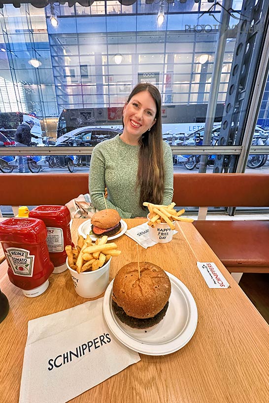 Reisebloggerin Biggi Bauer am Tisch mit zwei Burgern und Pommes bei Schnippers in New York