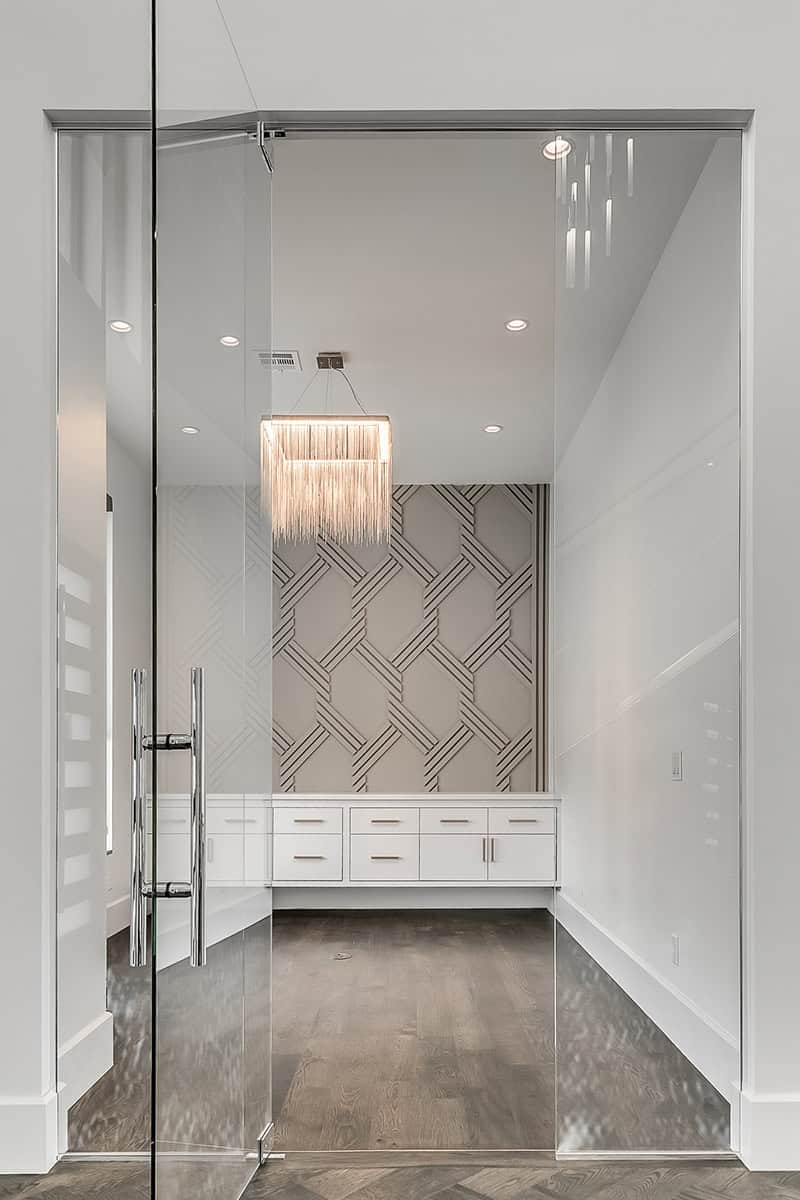 Stylish interior room with glass doors, chandelier, and custom cabinetry, featured in Oklahoma luxury homes.