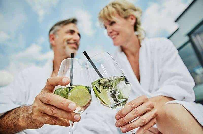 Ein Paar im Bademantel stößt mit einem Cocktail an