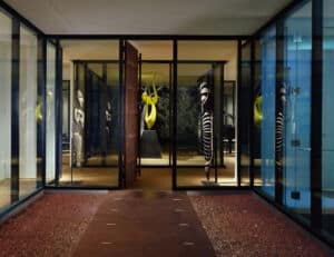 At 222 Residence, Rand Elliott Architects frames arrival as art—where architecture, sculpture, and shadow create a timeless first impression. Glass-walled residential entry with sculptures and warm lighting, designed by Rand Elliott Architects.