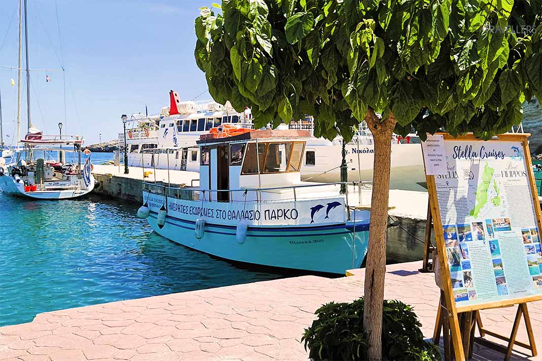 Ein kleines Ausflugsboot ankert nahe einem Baum im Hafen von Patitiri
