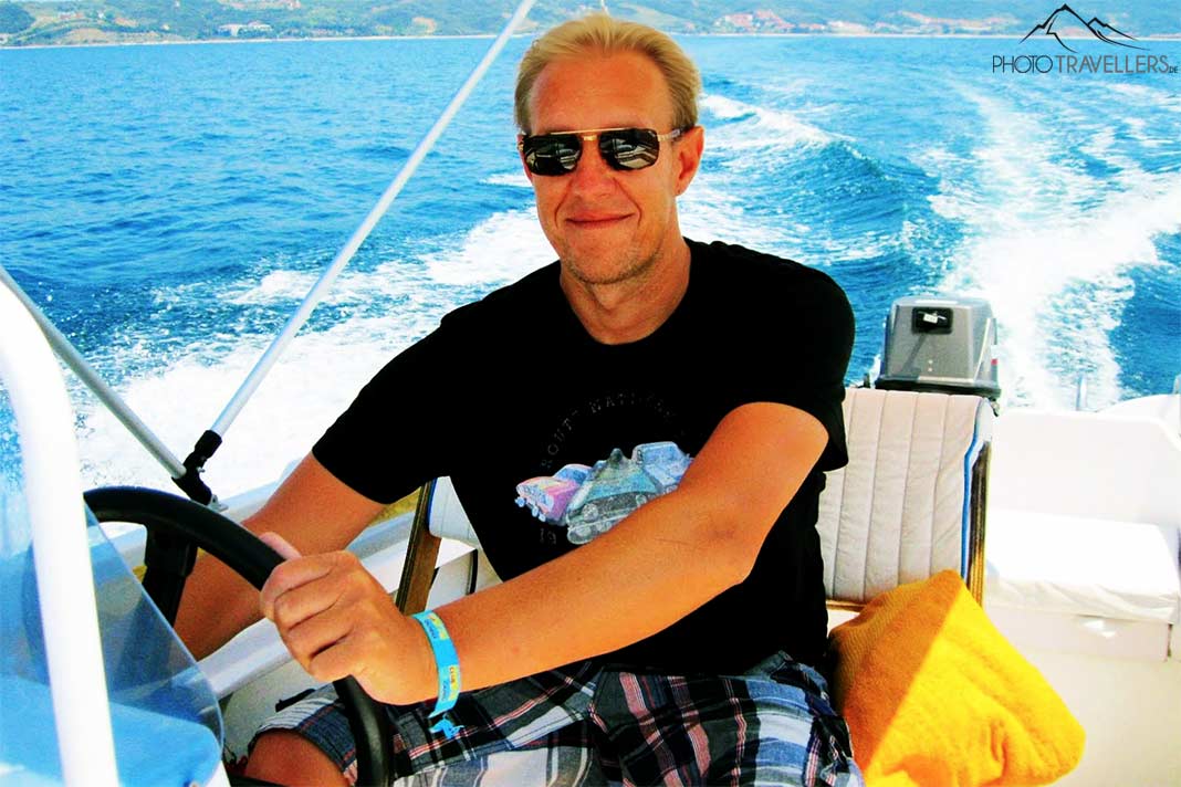 Ein blonder Mann hält das Lenkrad eines Bootes während der Fahrt