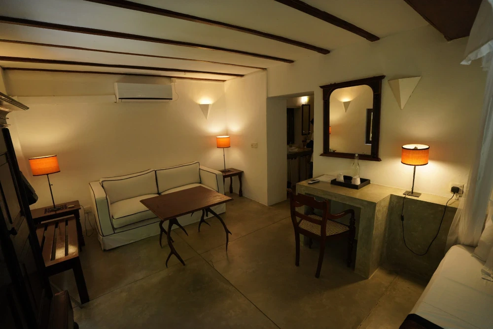 Interior of Adigar's manor's monkey puzzle room, showcasing a couch, table, and a mirror in a cozy setting.