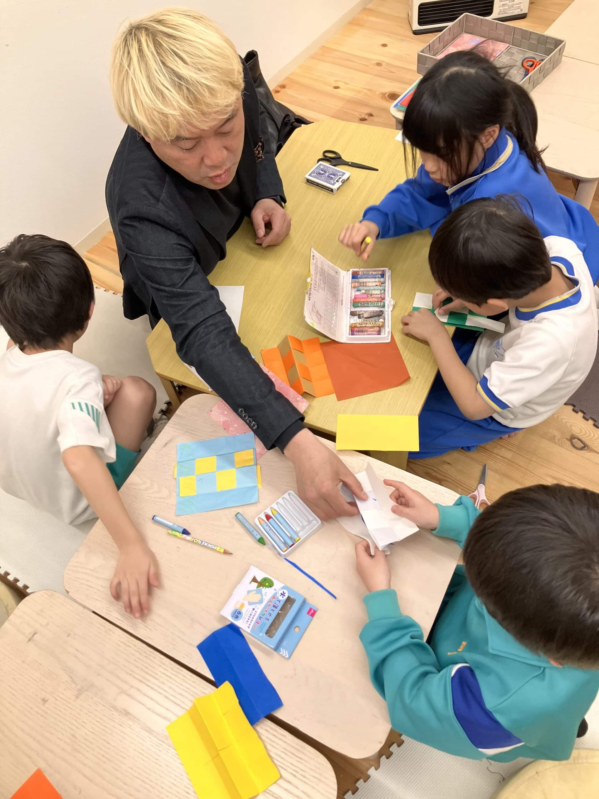学童保育でマジックショー!折り紙マジックに40分かけて挑戦した子どもたち 6 俯瞰から見た折り紙マジック制作の様子。ハサミやペンを使って真剣に取り組む子どもたち