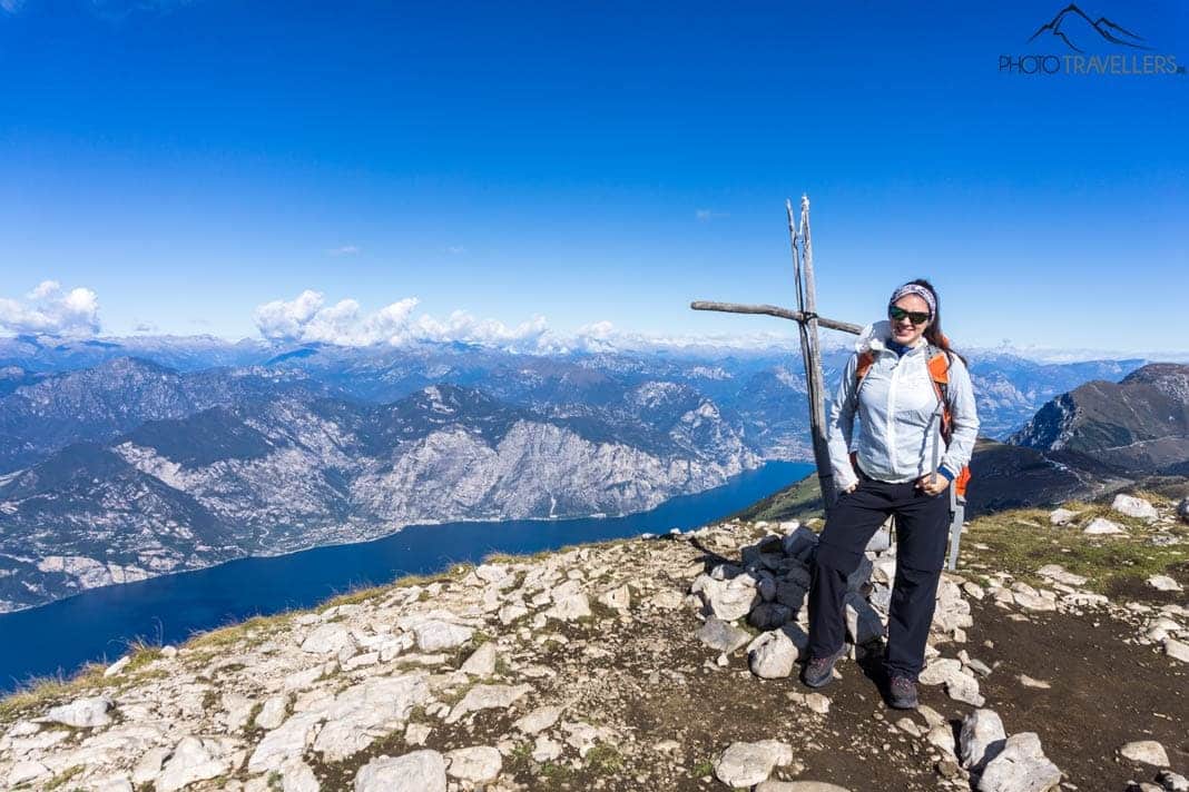 Reisebloggerin Biggi Bauer an einem kleinen Gifelkreuz auf dem Monte Baldo mit Blick auf den Gardasee