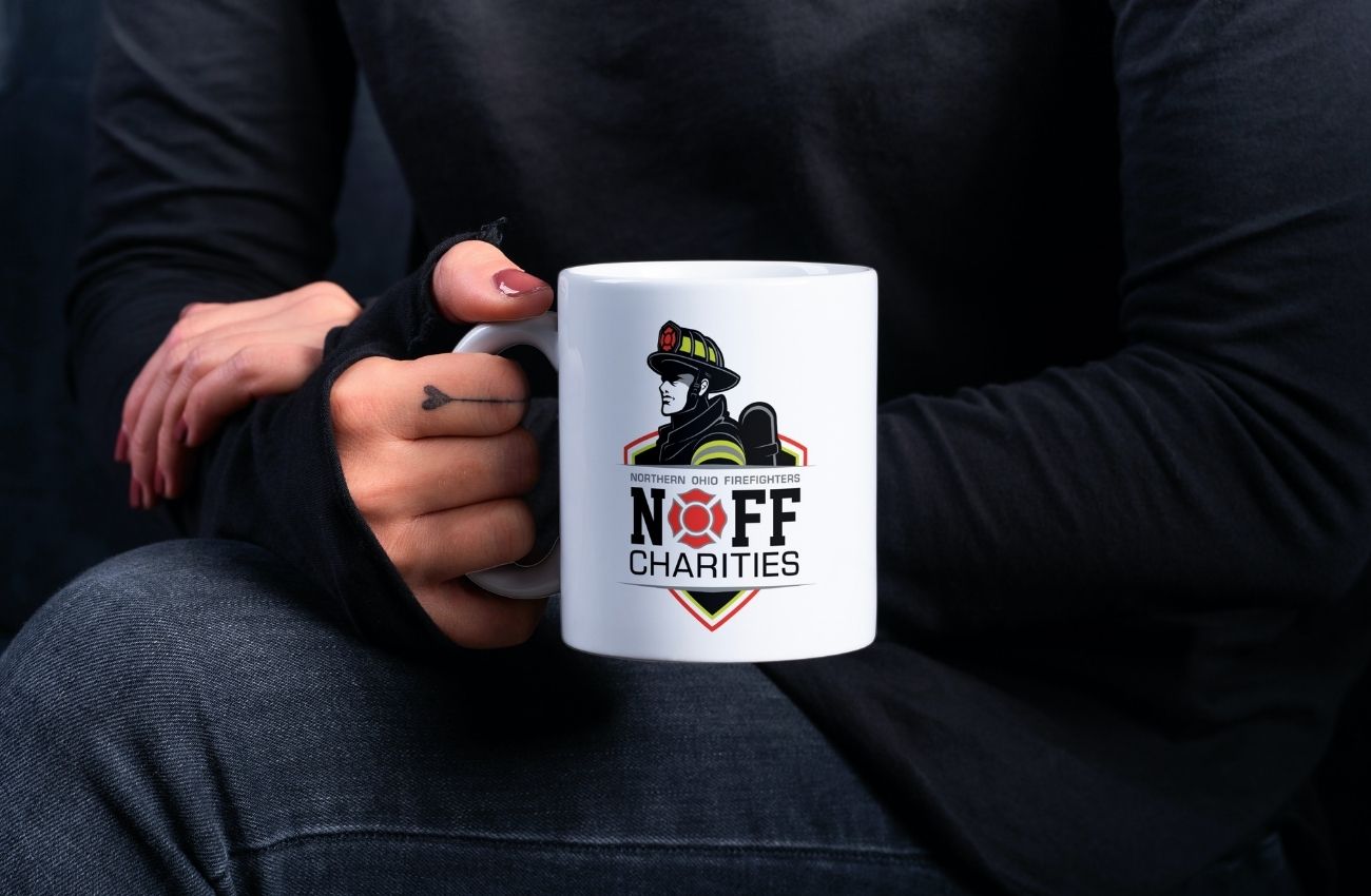 Person holding mug with firefighter logo; NOFF Charities