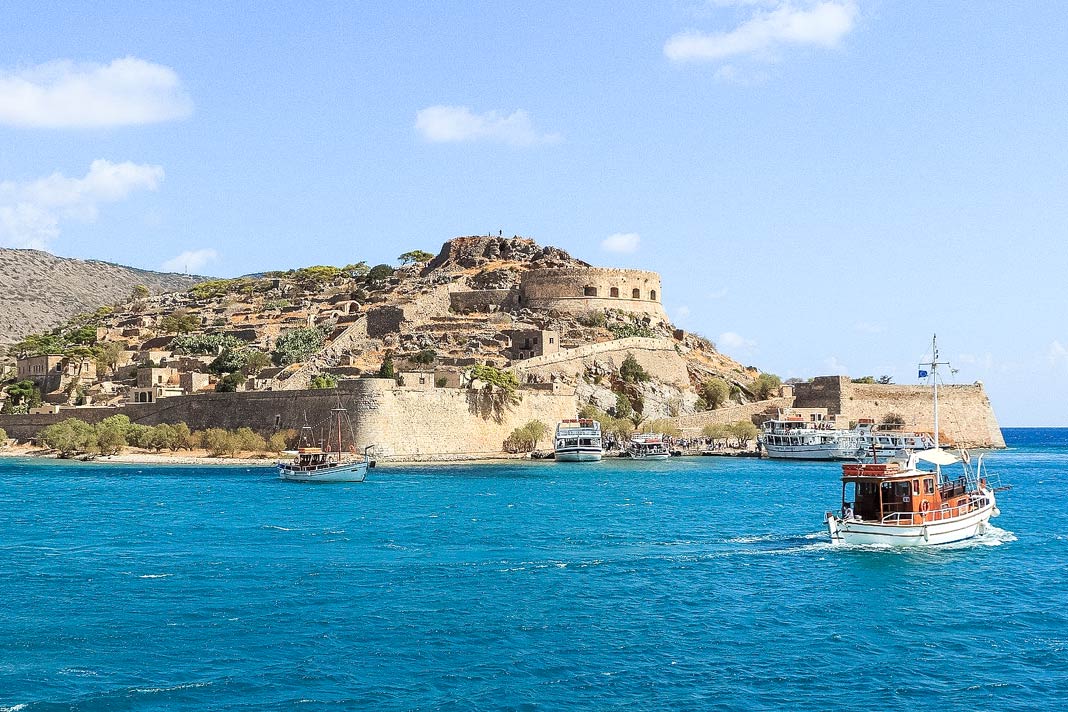 Blick auf die Insel Spinalonga mit der alten Lepra-Station, davor ein paar Boote