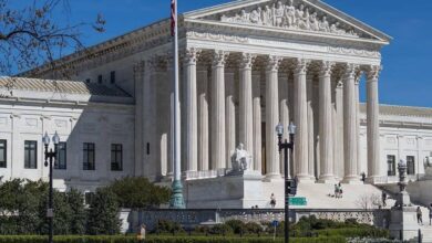The United States Supreme Court building in Washington, D.C., a neoclassical structure with towering columns and a flag waving in the blue sky. "Equal Justice Under Law" is inscribed above the entrance. This image may be relevant to discussions of *Florida courts* or *Federal probe* topics.